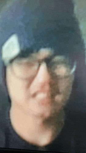 a blurry picture of a person 's face wearing glasses and a hat