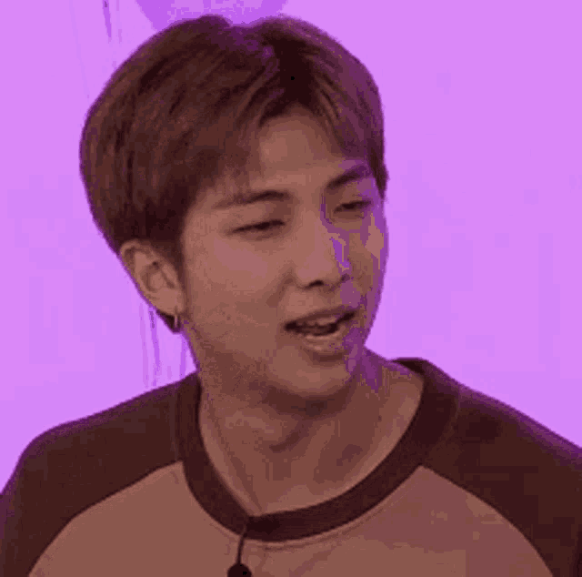 a close up of a man 's face with a purple background and a microphone in his mouth .