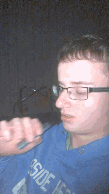 a man wearing glasses and a blue sweatshirt that says outside on it