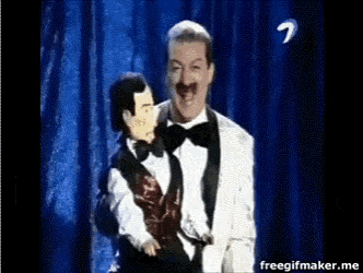 a man in a tuxedo is holding a puppet on a stage