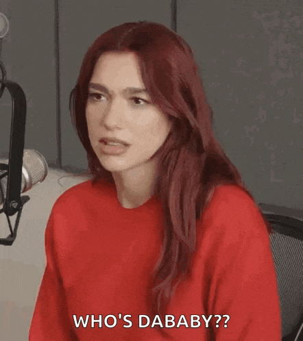 a woman with red hair is wearing a red sweater and sitting in front of a microphone .