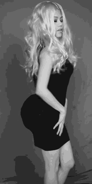 a black and white photo of a woman in a wig and a black dress
