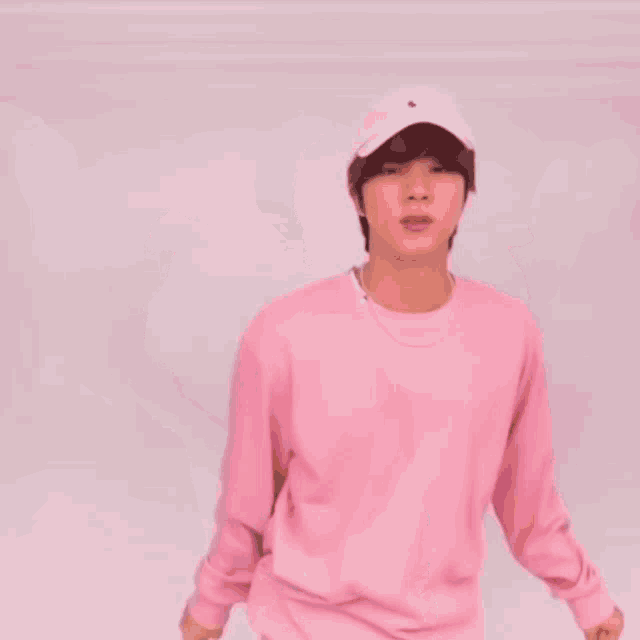 a young man wearing a pink sweatshirt and a pink hat is dancing .