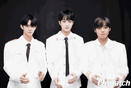 three young men in white suits and ties are standing next to each other in front of a black background .