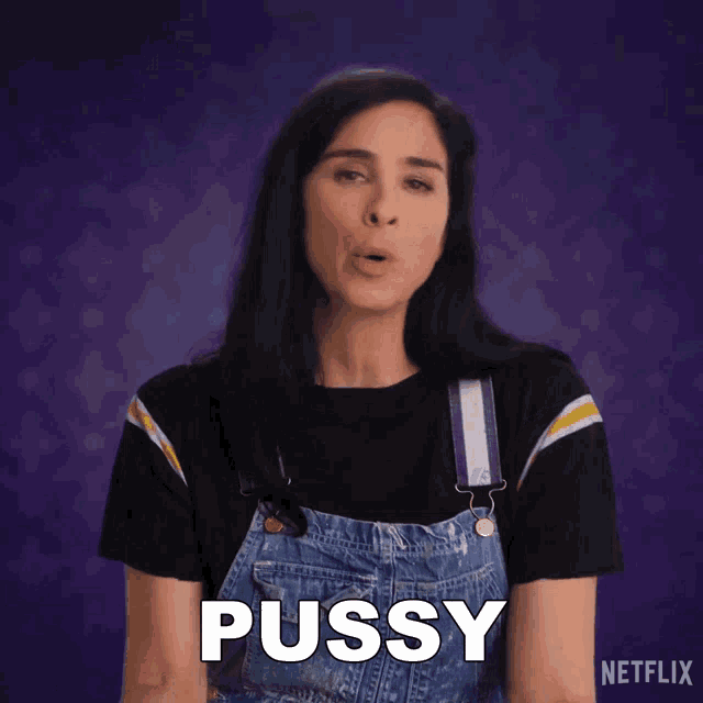 a woman in overalls says pussy in front of a purple backdrop