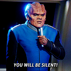 a man in a blue jacket is holding a microphone and saying you will be silent