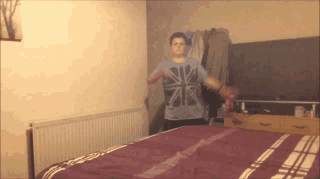 a man in a british flag shirt is standing in a bedroom