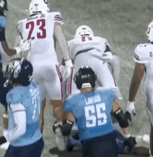 a football player with the number 23 on his jersey is being tackled by another player .