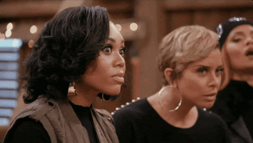 three women are standing next to each other and one of them has a surprised expression on her face