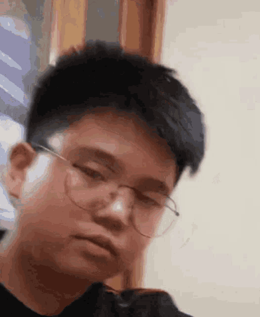 a young man wearing glasses is looking at something