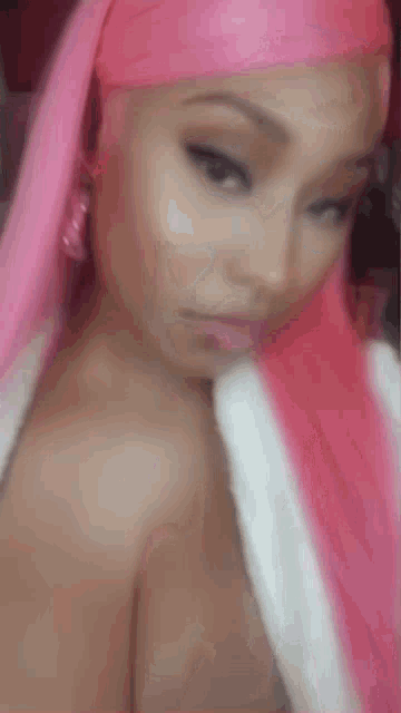a woman with pink hair is taking a selfie with a pink headband .