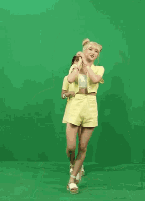 two girls in yellow clothes are dancing on a green screen