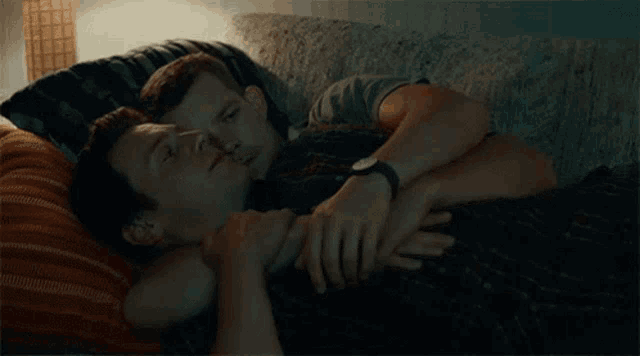 two men are hugging each other on a couch