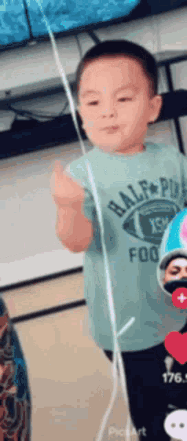 a young boy wearing a half pint shirt is giving the middle finger