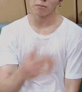a man wearing a white t-shirt is sitting on a couch with his hands on his chest .