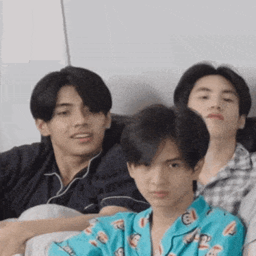 a group of young men are sitting on a couch together .