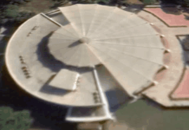 an aerial view of a large circular building with a roof