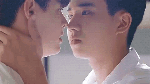 a couple of young men are kissing each other on the cheek .