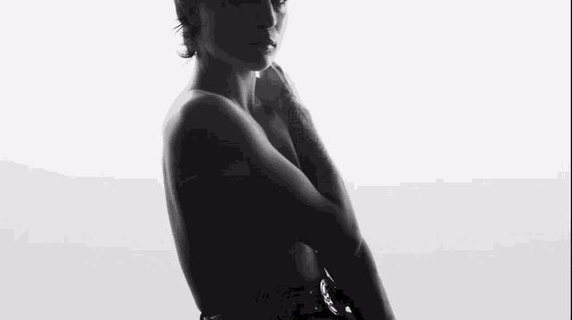 a black and white photo of a naked woman standing in front of a white wall .