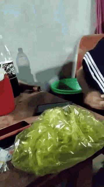 a bottle of soda sits on a table next to a bag of green chips
