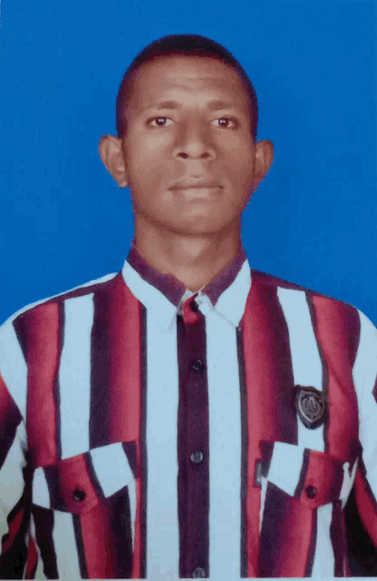 a man wearing a red and white striped shirt stands in front of a blue wall