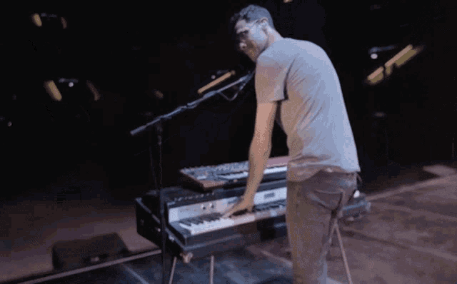 a man playing a keyboard in front of a microphone in a dark room