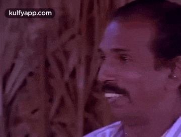 a man with a mustache is laughing while wearing a striped shirt .