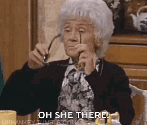 an elderly woman is sitting at a table holding a pair of glasses and says oh she there .