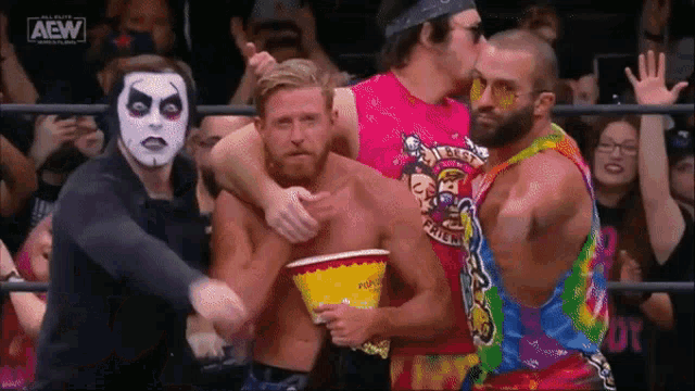 a group of wrestlers are standing in a ring and one of them is holding a yellow popcorn bucket .