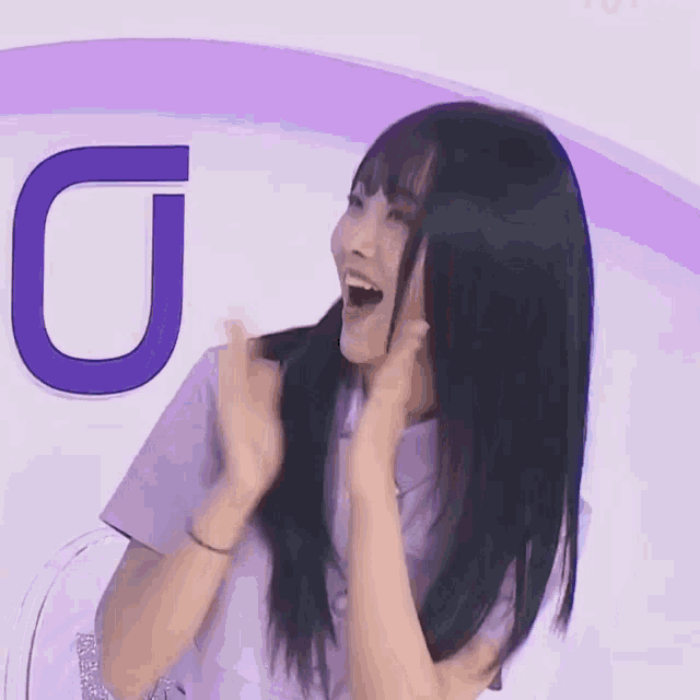 a woman in a purple shirt is standing in front of a letter u
