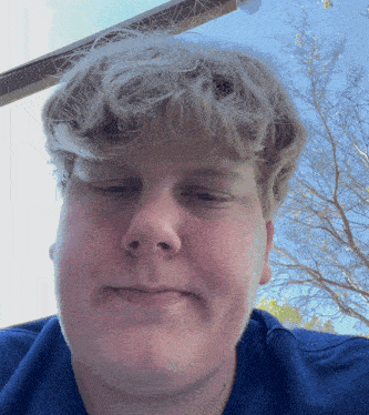 a man with blonde hair and a blue shirt is smiling