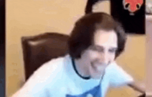 a man in a white shirt is sitting in a chair laughing .