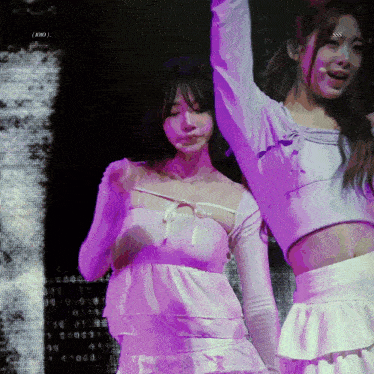 two girls are dancing on a stage with a purple background