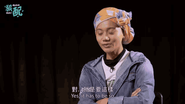a woman wearing a head scarf and a denim jacket with the word yes on the back