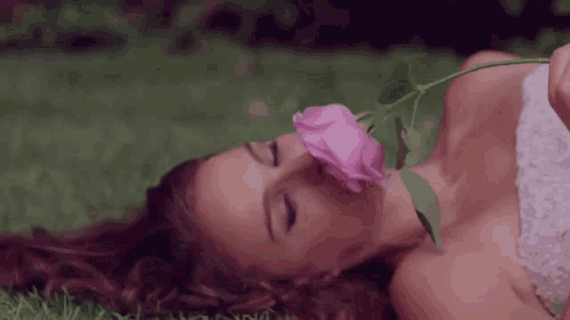 a woman in a white dress smells a pink rose