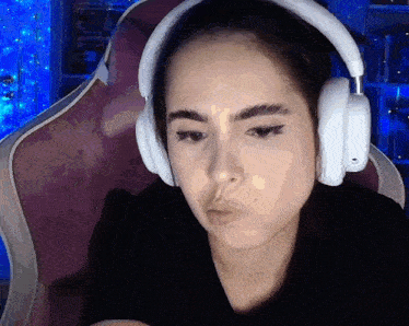 a woman wearing headphones is sitting in a chair and making a funny face .