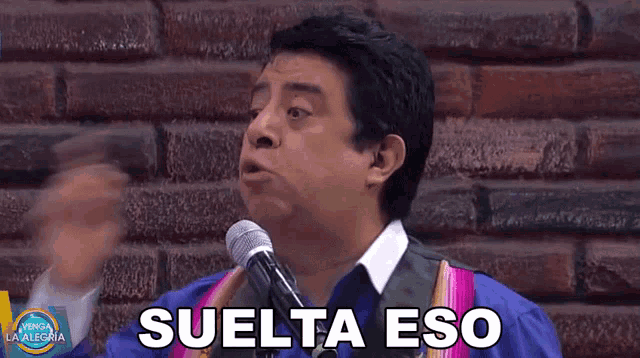 a man speaking into a microphone with the word suelta eso written on his face