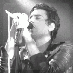 a man in a leather jacket is singing into a microphone .