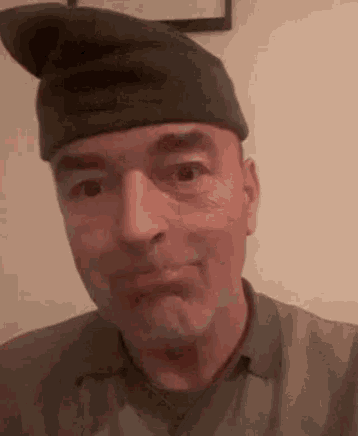 a man wearing a hat is making a face .
