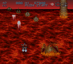 a video game screen shows a giant pillar in the middle of a lava field and says push start