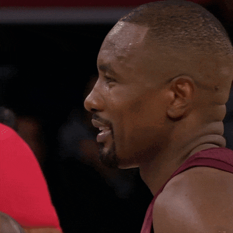 a man with a beard is talking to another man in a red shirt