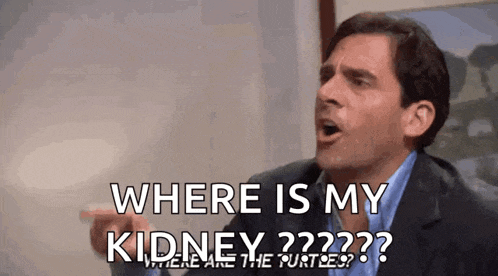 a man in a suit and blue shirt is pointing at something and asking where is my kidney ?