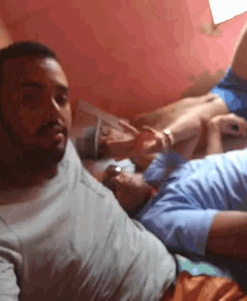 a man in a white shirt is laying on a bed next to another man in a blue shirt .