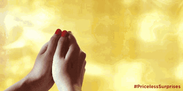 a woman with red nail polish holds her hands together with the hashtag pricelesssurprises