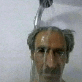 a man with a beard is taking a shower with water coming out of the shower head