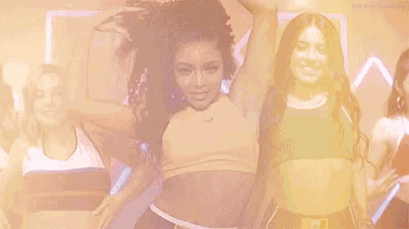 a group of young women are dancing together and one of them is wearing a yellow crop top .