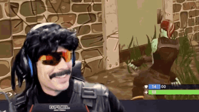 a man wearing sunglasses and a wig is playing a video game with a gfuel logo on his monitor
