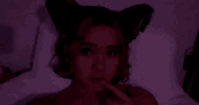 a woman is laying on a bed in a dark room with headphones on her head .