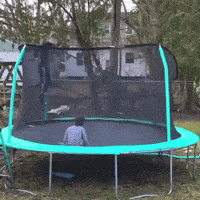 a child is sitting on a trampoline with a fence around it
