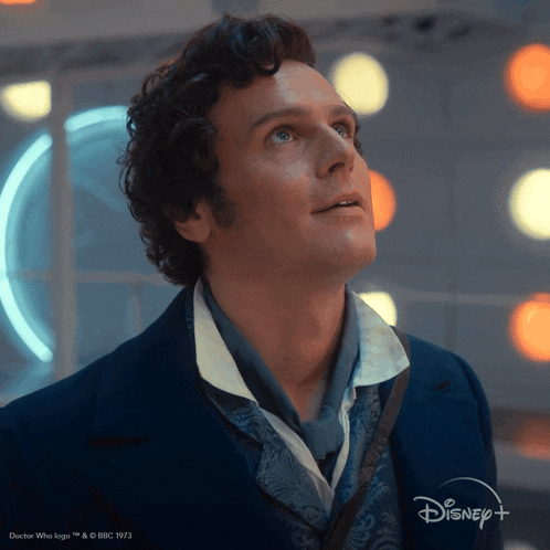 a man in a blue suit with a disney logo on the bottom right